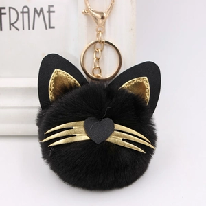 Close-up of a black faux fur cat keychain with golden whiskers and heart-shaped nose