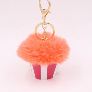 Detail of fluffy orange faux fur cupcake keychain with gold metal clasp and striped base