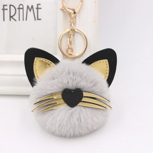 Plush grey cat pompom keychain with golden whiskers and black heart nose for bag charm