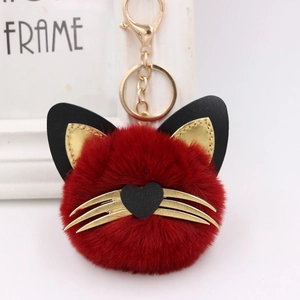 Detailed macro view of a red fluffy cat keychain with gold whiskers and a golden lobster clasp