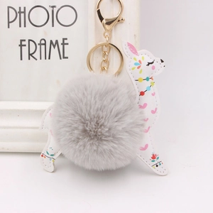 Detail of white alpaca keychain with colorful patterns and a grey faux fur ball