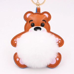 Détail d'un porte-clés ours en cuir marron avec pompon blanc doux et anneau doré