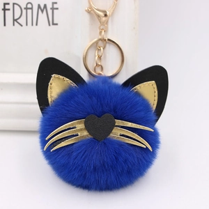 Detail of dark blue plush cat keychain with golden whiskers and metal lobster clasp