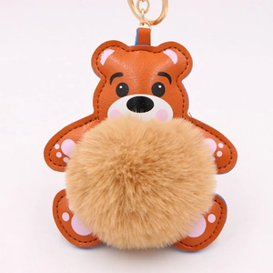 Détail d'un porte-clés ours en peluche marron avec pompon doux et fermoir doré