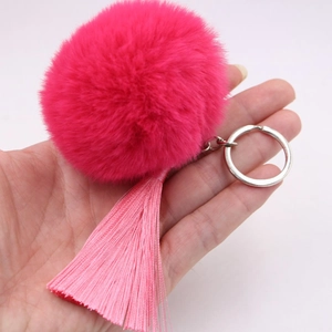 Detail of soft rose red faux fur pompom with pink tassel and silver keychain