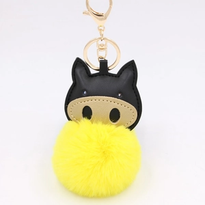 Detail of creative pig keychain with yellow plush pompom and black leather animal head
