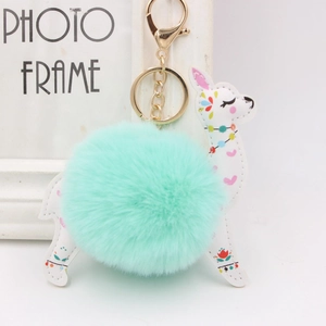 Detail of alpaca keychain with mint green faux fur pompom and printed leather design