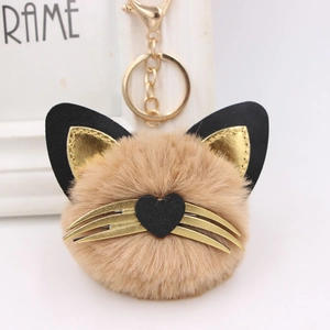 Detail showing plush cat keychain with heart nose, whiskers, and gold metal hardware