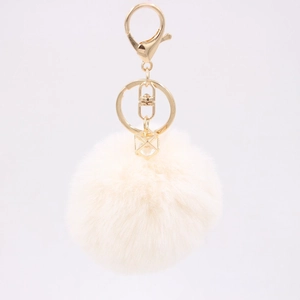 Detail of a beige faux fur keychain with gold-tone hardware and geometric crystal pendant