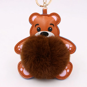 Détail d'un porte-clés ours en cuir marron avec pompon en fourrure et attache dorée