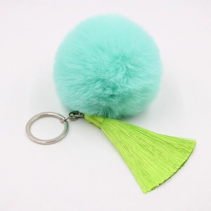 Detail of mint green faux fur pompom and matching silk tassels on silver keychain