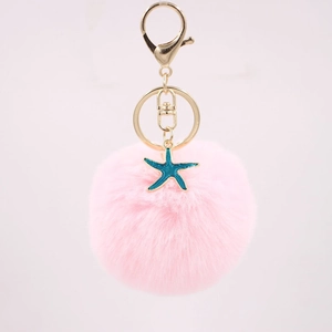 Close-up of pink pompom keychain with teal starfish charm and gold metal lobster clasp
