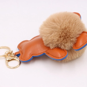 Détail d'un porte-clés ours en peluche avec cuir orange et bords bleus peints