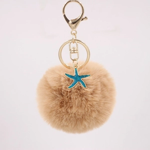 Detailed close-up of fluffy khaki pompom keychain with golden clasp and blue starfish charm