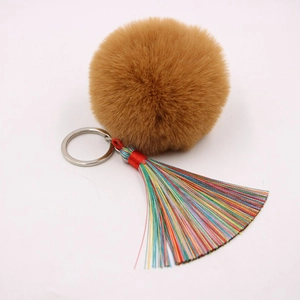 Makro-Detail von buntem Boho-Quasten und braunem Plüsch-Pompon am silbernen Schlüsselring