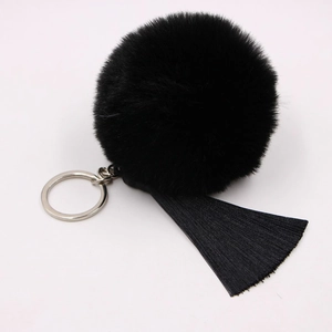 Detail of a fluffy black faux fur pompom with long tassels and silver metal keyring