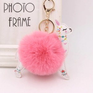 Detail of alpaca plush keychain with pink pom-pom, white leather, and gold lobster clasp