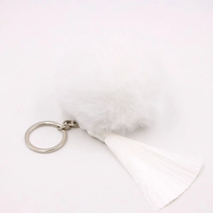 Detailed macro view of white faux fur pompom and long tassel on a silver keychain