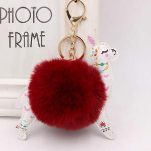 Macro shot of red faux fur pompom and printed PU leather deer charm with golden clasp
