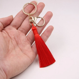 Détail d'un porte-clés à pompon en soie rouge vif avec fermoir en métal doré