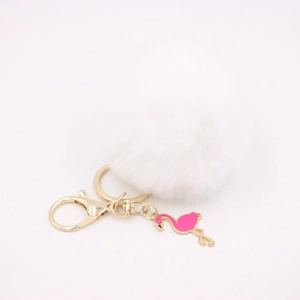 Detail of a white faux fur ball keychain with gold hardware and pink flamingo charm