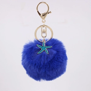 Detailed view of fluffy navy blue pompom keychain with a teal starfish charm and golden ring
