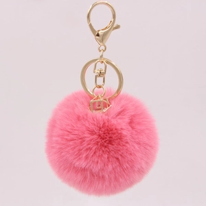 Detailed close-up of pink faux rabbit fur pom pom keychain with gold metal hardware
