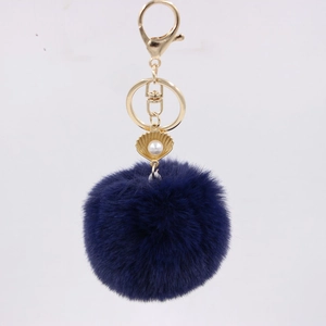 Close-up of navy blue faux rabbit fur keychain with gold shell and pearl detail