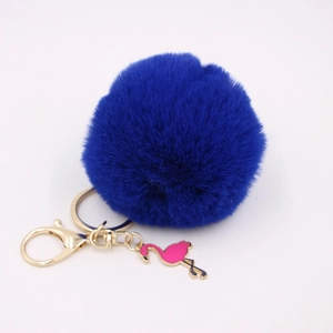 Close-up of royal blue faux fur pompom with a pink flamingo charm and gold keychain