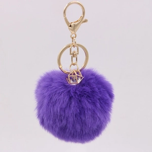 Detail of purple faux rabbit fur keychain with gold lobster clasp and gemstone pendant
