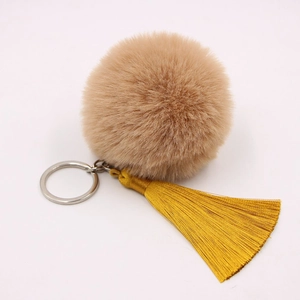 Detail of soft brown plush pom pom with golden silk tassels and silver key ring