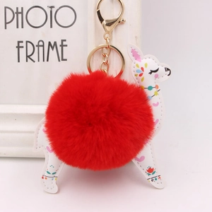 Detail of creative white leather alpaca keychain with red pompom and gold lobster clasp