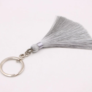 Detailed macro view of silky silver-grey bohemian tassel pendant with metallic key ring