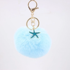 Detailed close-up of light blue faux fur pompom keychain with a teal starfish pendant