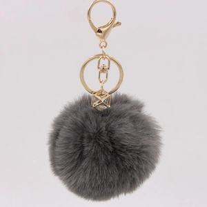 Close-up of dark grey faux fur keychain with gold geometric pendant and lobster clasp