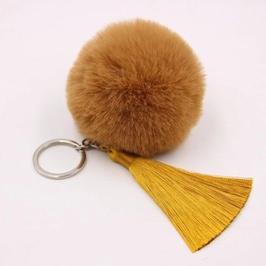 Detailed view of bohemian keychain with tan faux fur pom pom and yellow silk tassel