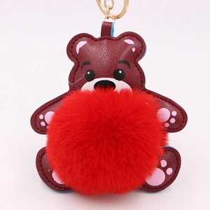 Détail d'un porte-clés ours en cuir rouge avec un grand pompon rouge et anneau doré