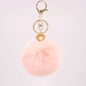 Close-up of pink faux rabbit fur keychain with gold shell and white pearl detail