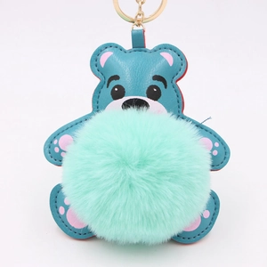 Détail d'un porte-clés ours en cuir bleu avec pompon vert menthe doux et anneau doré