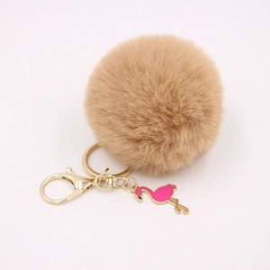 Detail of camel faux fur pom pom keychain with gold ring and pink flamingo charm