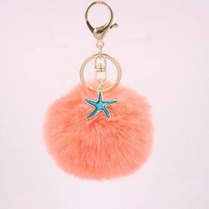 Detail of coral orange pompom keychain with a turquoise starfish charm and gold ring