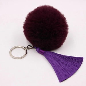 Detail of burgundy faux fur pompom and purple silk tassel on silver keychain