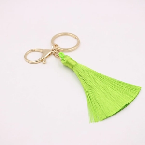 Détail du porte-clés à pompon en soie vert fluo avec fermoir mousqueton en métal doré