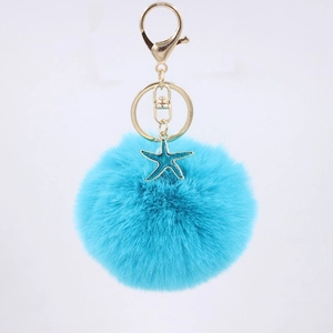 Detail of blue faux fur pompom keychain with golden lobster clasp and starfish charm