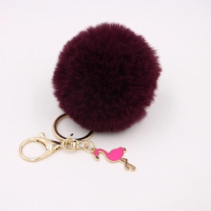 Detail of burgundy faux fur pompom keychain with golden clasp and pink flamingo charm