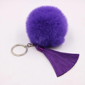 Detailed close-up of a purple faux fur pompom and silk tassel keychain with silver ring