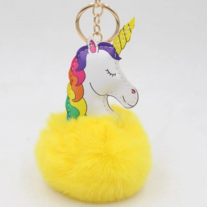 Détail d'un porte-clés licorne en cuir PU blanc avec un pompon jaune en fausse fourrure douce