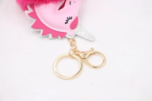 Detail of pink plush unicorn keychain with magenta faux fur pom pom and gold metal clasp