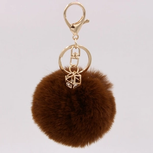 Detail of a brown faux rabbit fur keychain with gold hardware and a geometric gemstone charm