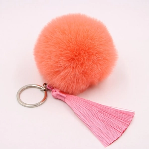 Macro shot of fluffy orange faux fur keychain with pink silk tassels and silver metal ring